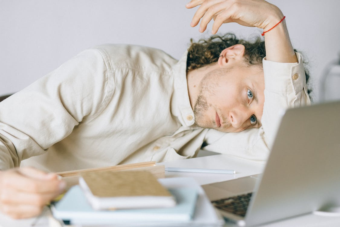 A person feeling tired and sluggish working on their computer