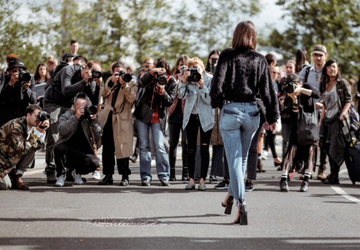 An image of a woman walking on the street with paparazzi taking pictures