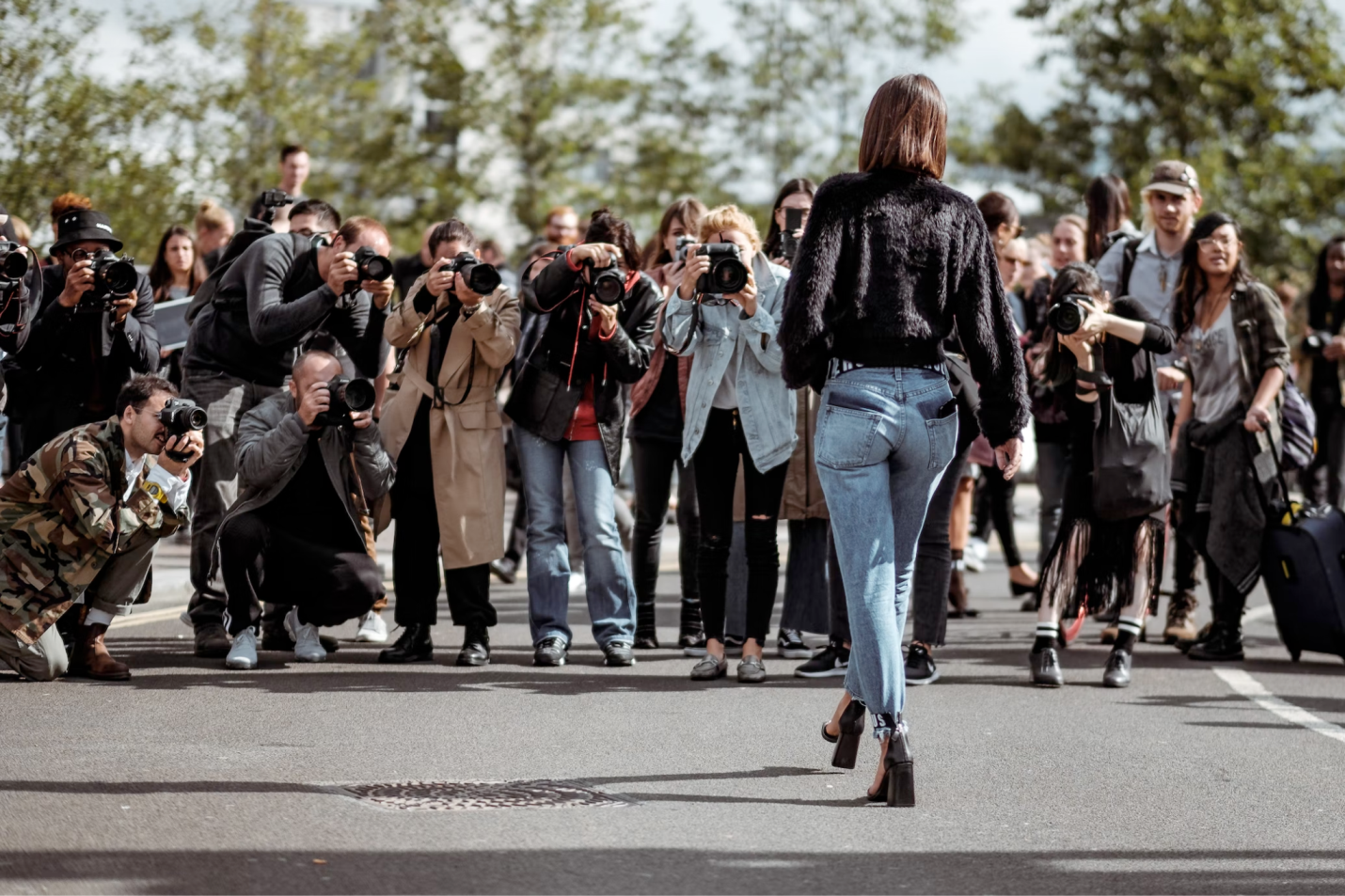 An image of a woman walking on the street with paparazzi taking pictures